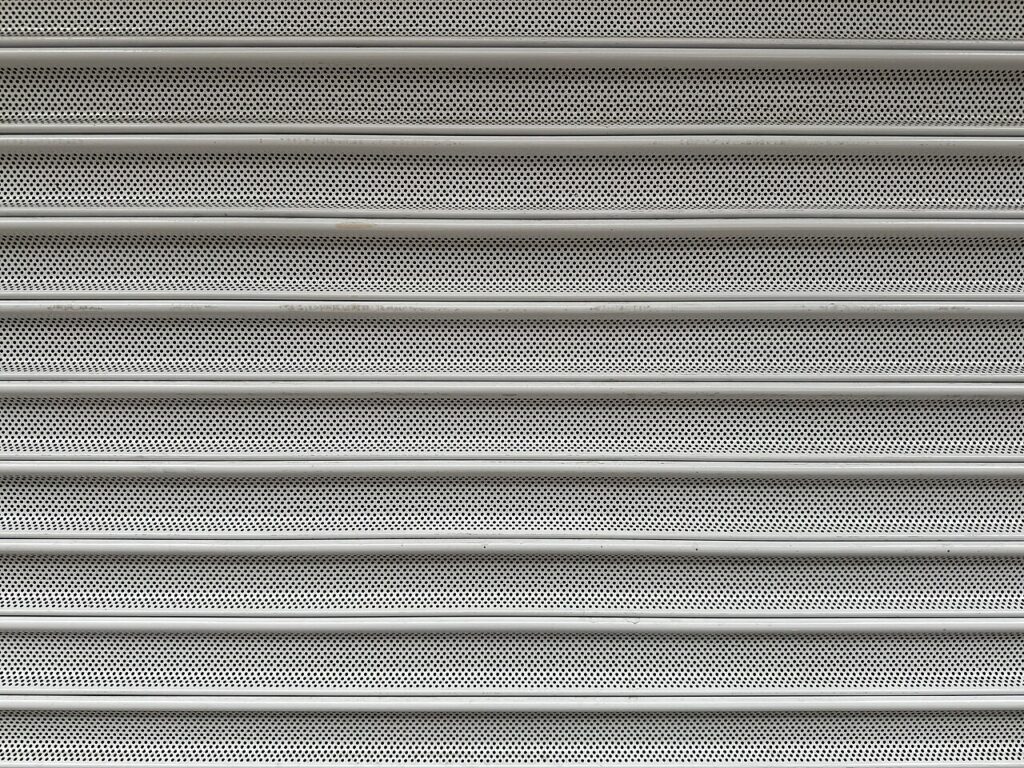 Detalhe de lâminas metálicas microperfuradas de uma porta de enrolar elétrica