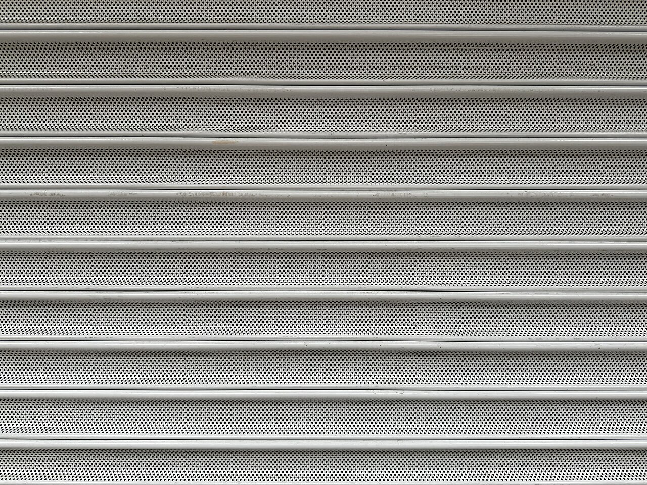 Detalhe de lâminas metálicas microperfuradas de uma porta de enrolar elétrica