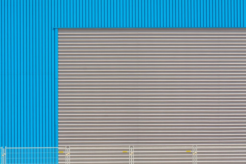 Porta de enrolar metálica fechada em fachada industrial azul