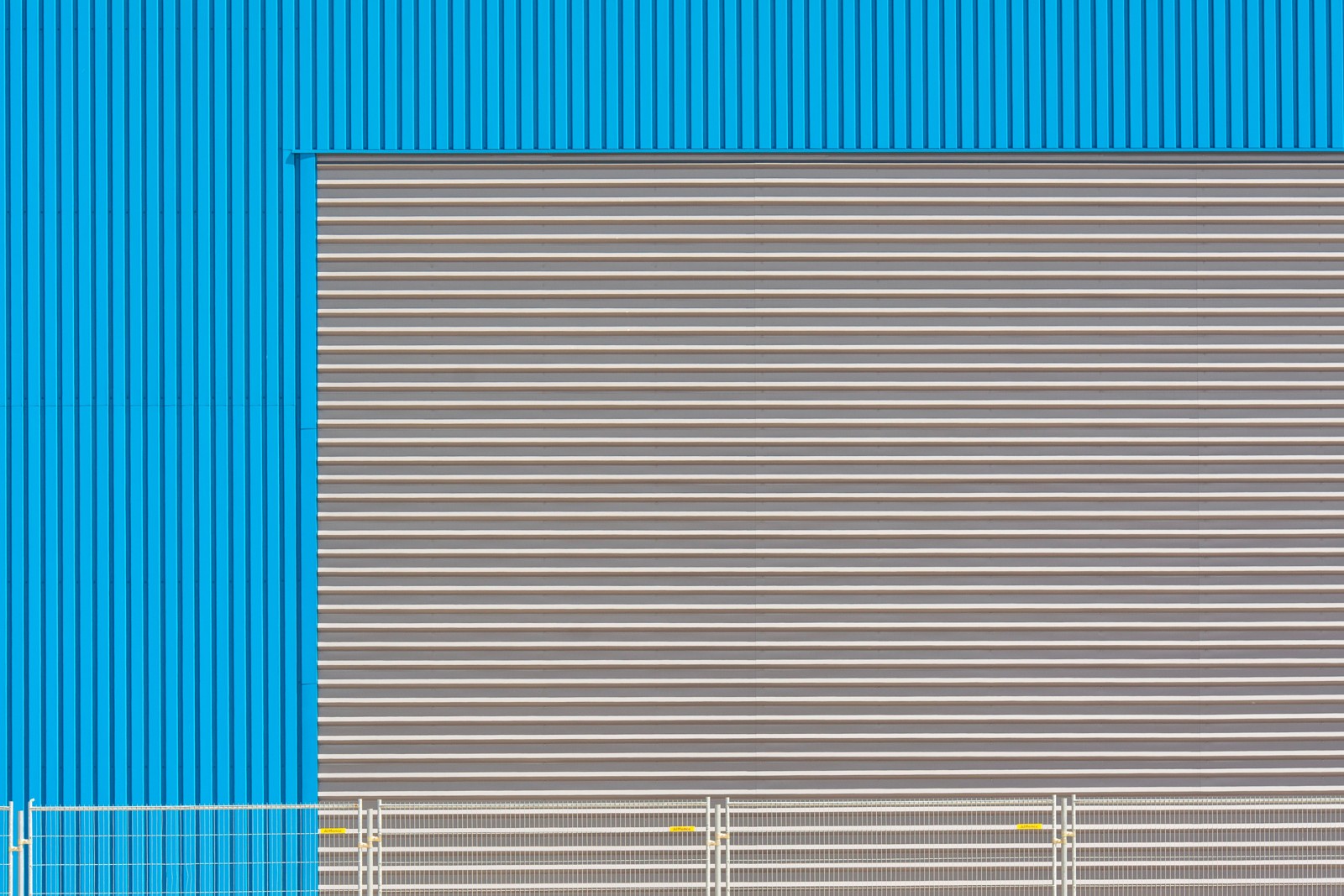 Porta de enrolar metálica fechada em fachada industrial azul